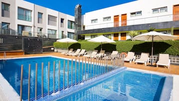 Ein modernes Hotel mit Swimmingpool, Liegestühlen und Sonnenschirmen.