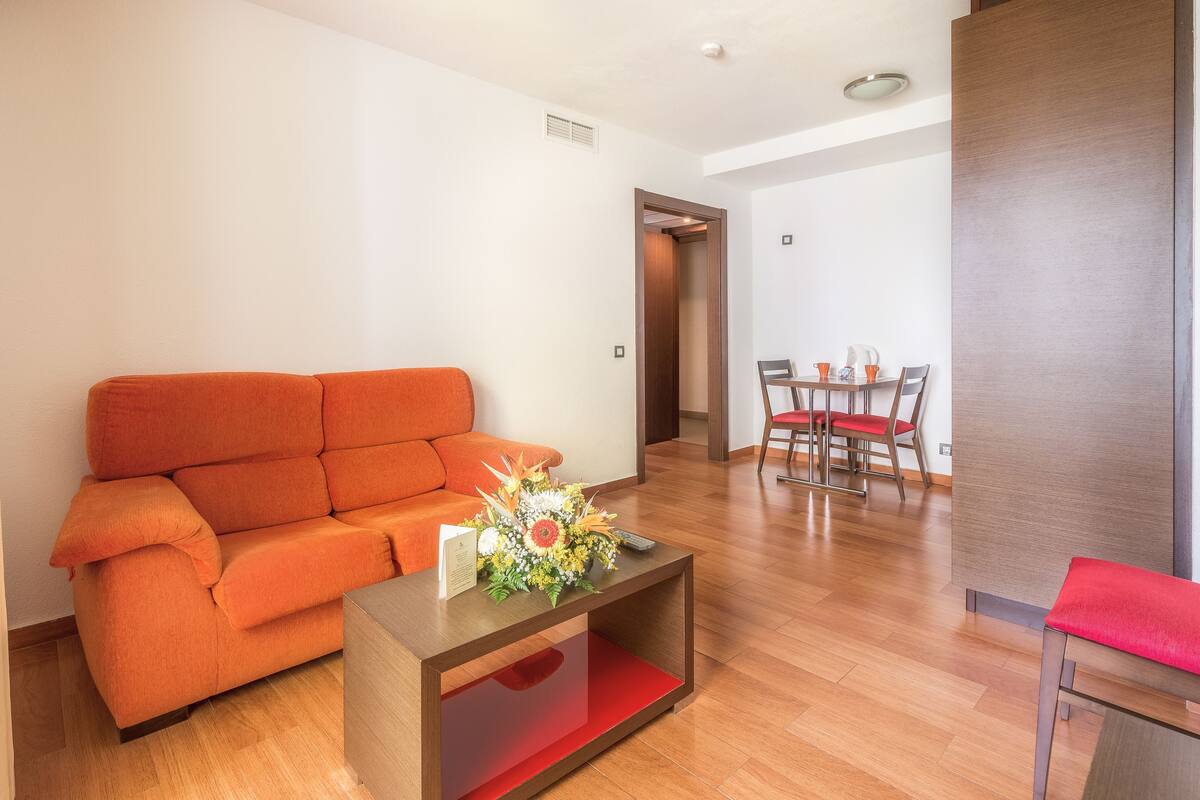 Un salon moderne comprenant un canapé, une table basse agrémentée d’un arrangement floral et un coin repas avec des chaises et une table.