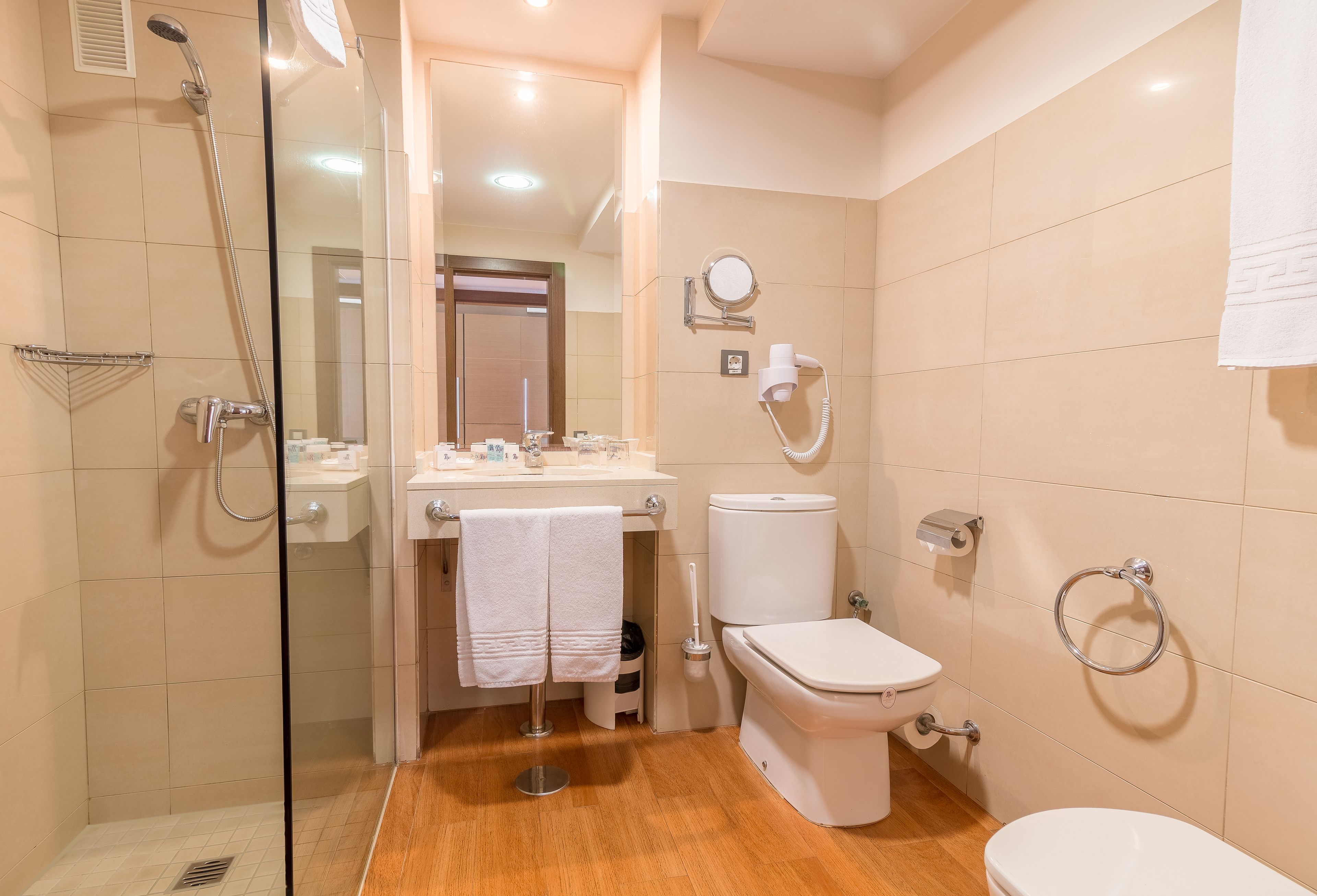 A modern bathroom with a glass-enclosed shower, a toilet, and a sink with a mirror.