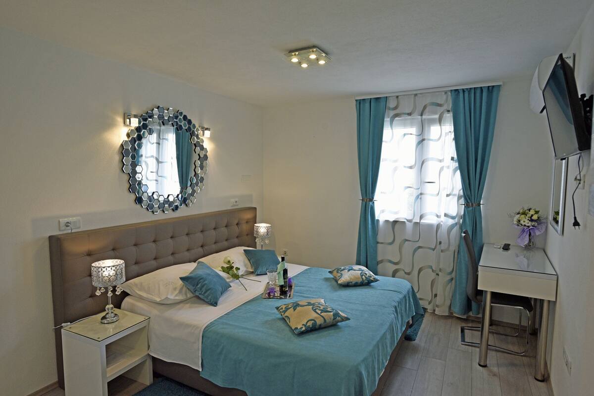 Ein ordentlich eingerichtetes Schlafzimmer mit Bett, Nachttischen, Schreibtisch und Spiegel.
