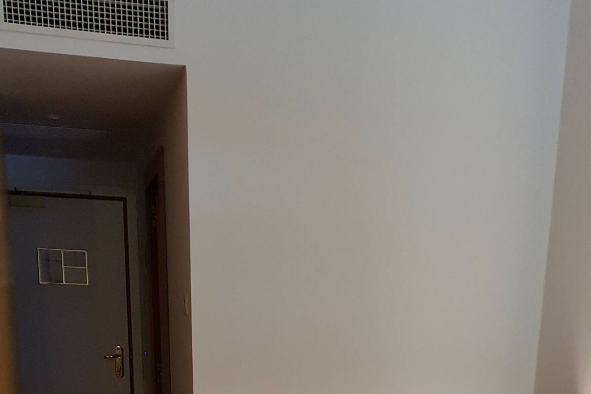 Une chambre à coucher avec un lit, une tête de lit en bois, un coussin à motifs zébrés et une porte donnant sur une autre pièce.