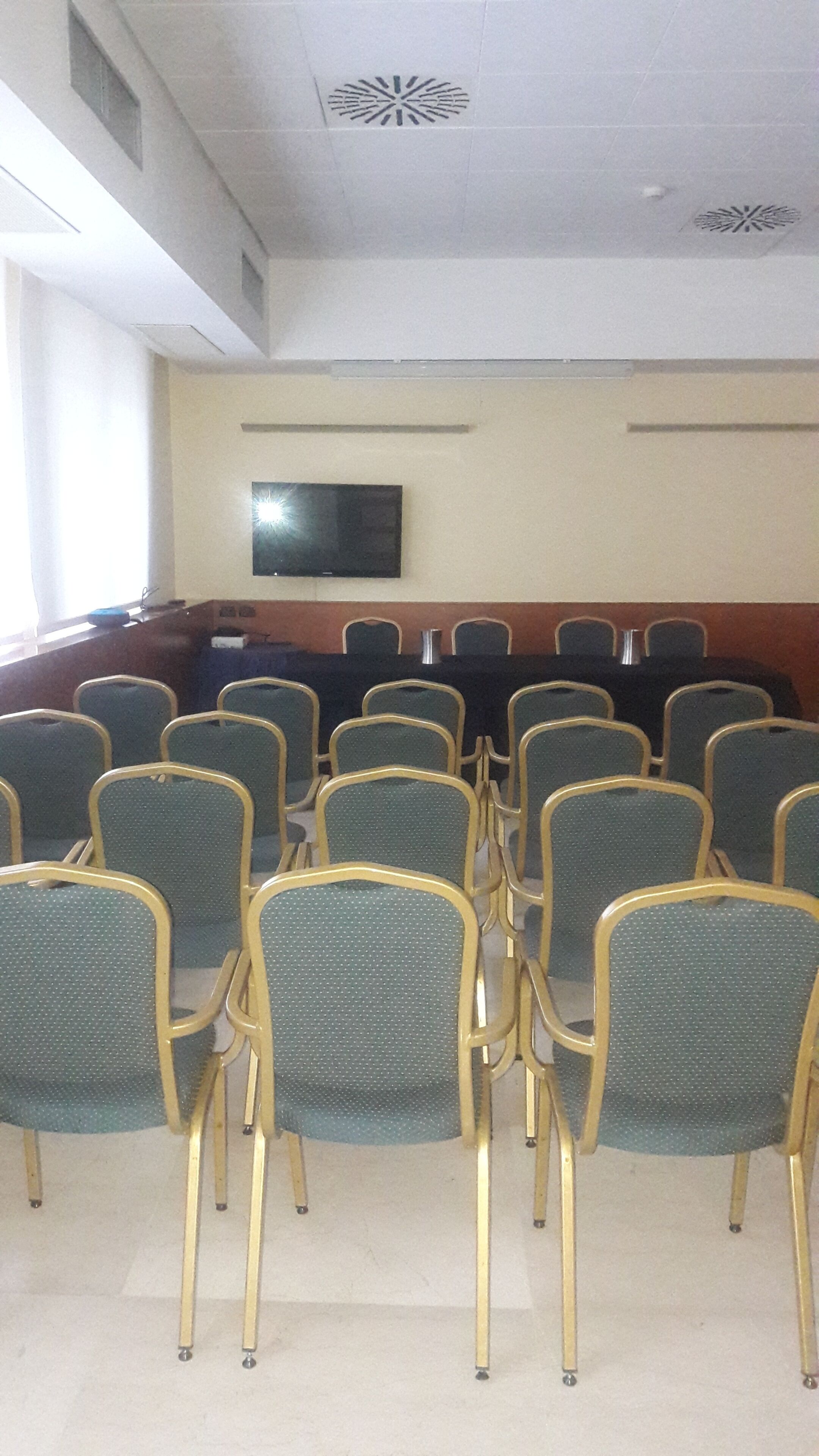 Ein Konferenzraum mit Reihen von Stühlen und einem Flachbildfernseher an der Wand.