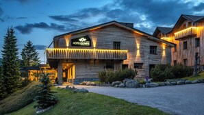 Un hotel con fachada de madera, un balcón con luces y un letrero que dice HOTELOLYMPIE.