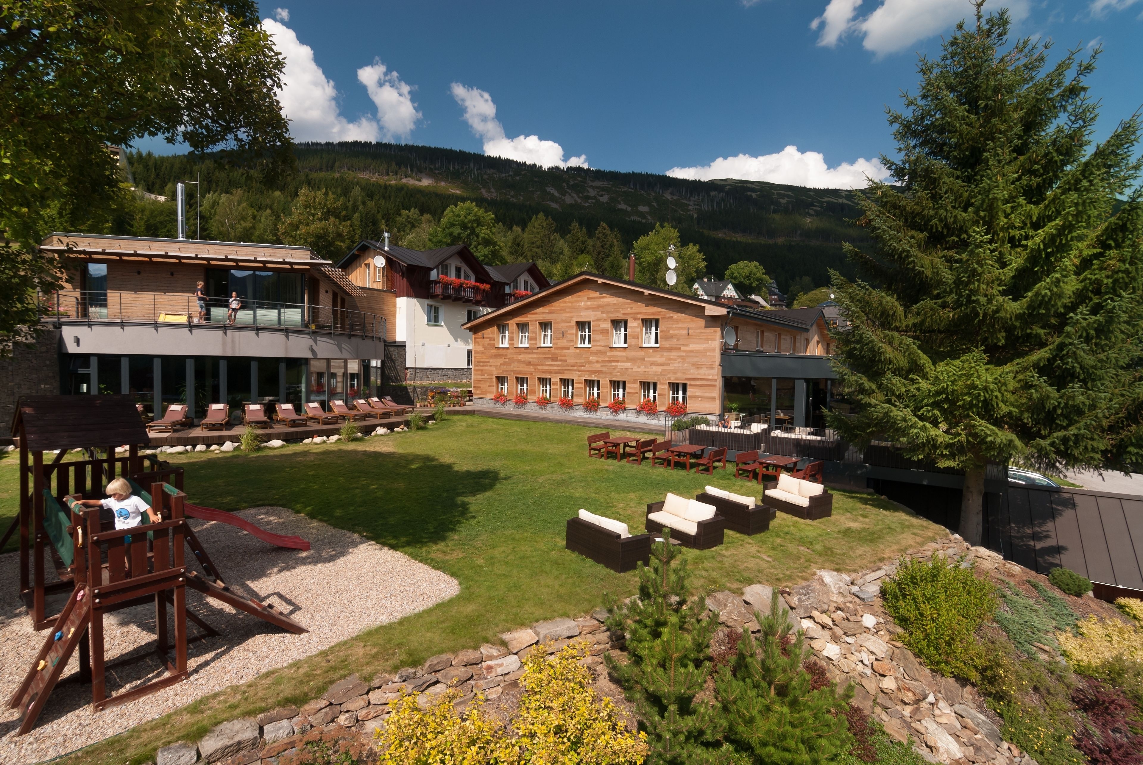 A hotel with a large outdoor area featuring a play structure, outdoor seating, and a view of a mountainous landscape.