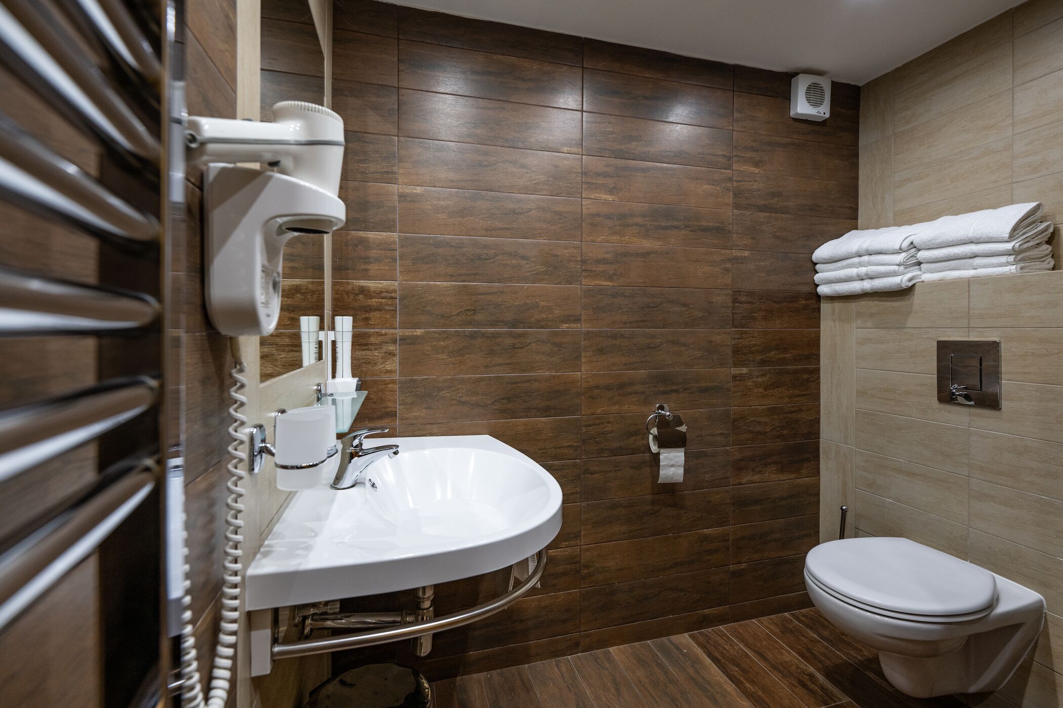 Ein modernes Badezimmer mit integriertem Waschbecken, Toilette und Handtuchhalter.
