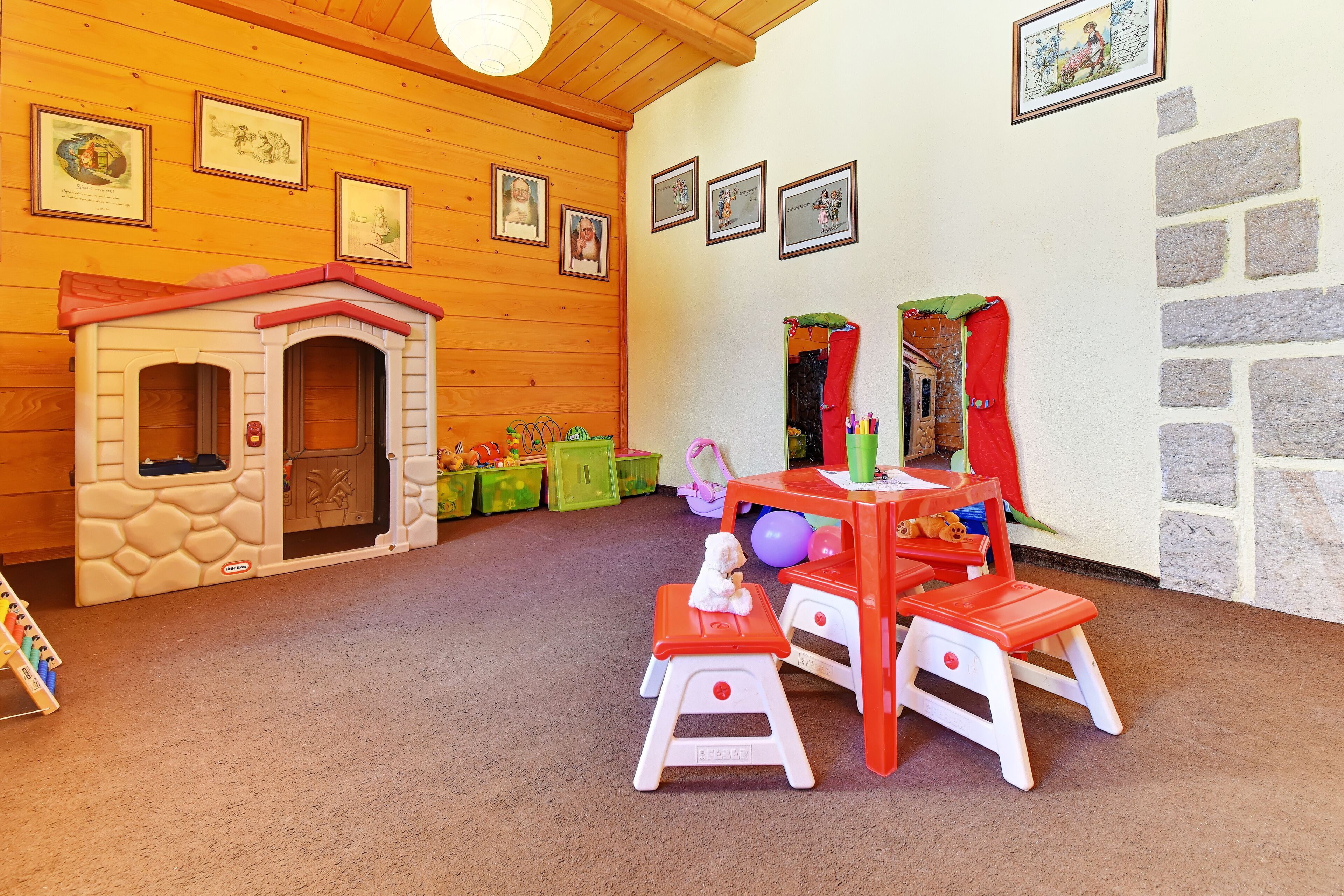 A children's play area with a playhouse, a table with chairs, and a small stool.