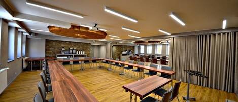 A conference room with long tables, chairs, and a wooden floor.