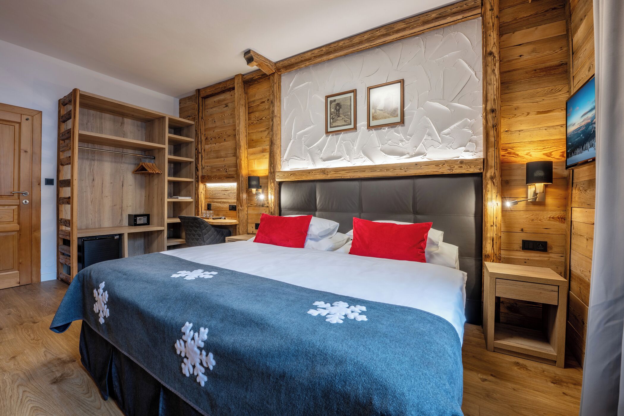 A bedroom with a large bed, wooden walls, a built-in wardrobe, and a nightstand with a lamp.