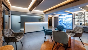 Un área de recepción moderna con techo de madera, una mesa de recepción y asientos con vistas a un paisaje nevado a través de un ventanal grande.