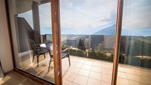 A balcony with a glass door, a table, and two chairs. - Kronplatz Resort Hotel Kristall (Valdaora)