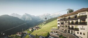 A hotel with a view of mountains, a ski lift, and a parking lot. - Kronplatz Resort Hotel Kristall (Valdaora)