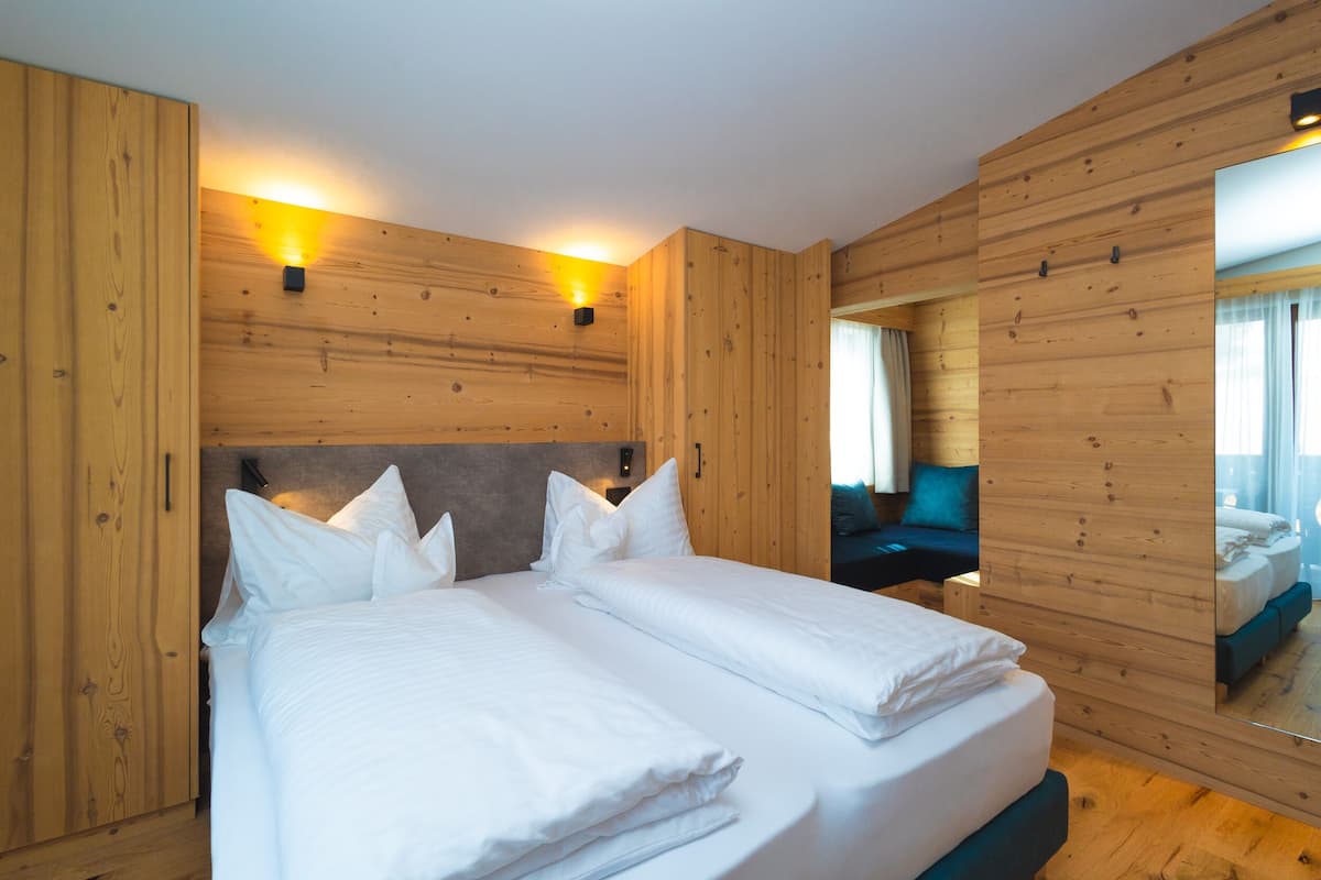 Ein modernes Schlafzimmer mit Holzwandverkleidung, einem großen Bett mit weißen Leinen und zwei Wandleuchten.