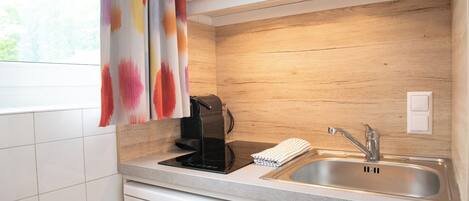 Une cuisine moderne équipée d’un lave-vaisselle encastré, d’une machine à café et d’un évier en acier inoxydable.