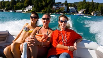 Tres personas en un bote, con vistas a casas y árboles al fondo.