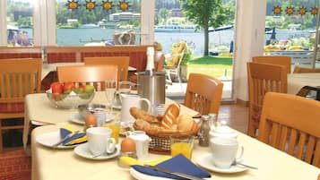 A breakfast table set with plates, cups, and a fruit bowl.