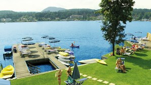 Un complexe hôtelier au bord du lac, doté d’un quai, de bateaux et d’une pelouse aménagée avec des chaises longues et des parasols.