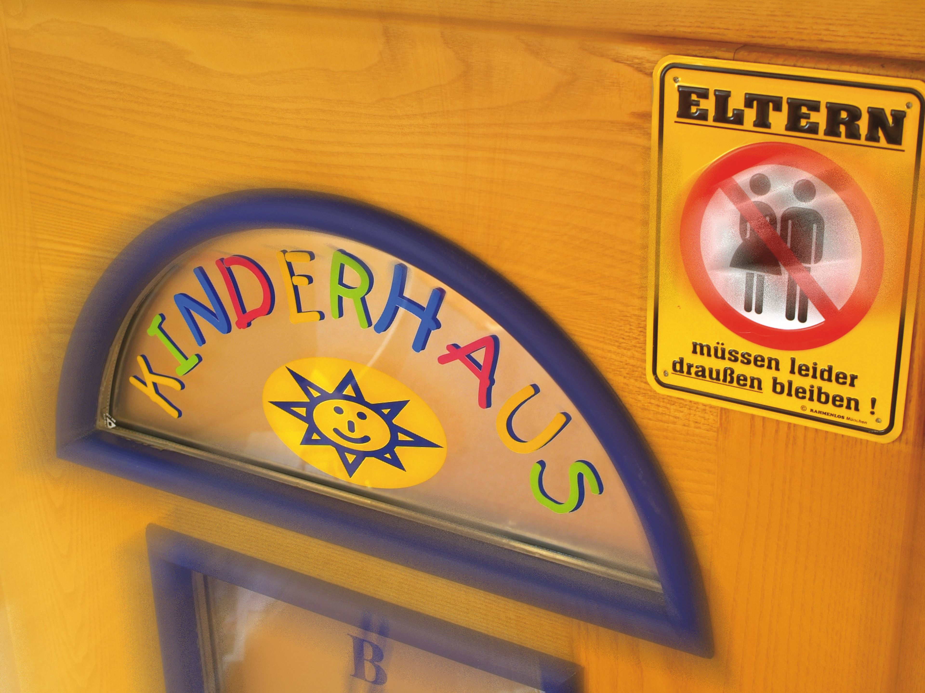Schild für einen Kinderspielbereich mit Sonne und lächelndem Gesicht, sowie ein Verbotsschild für Erwachsene.