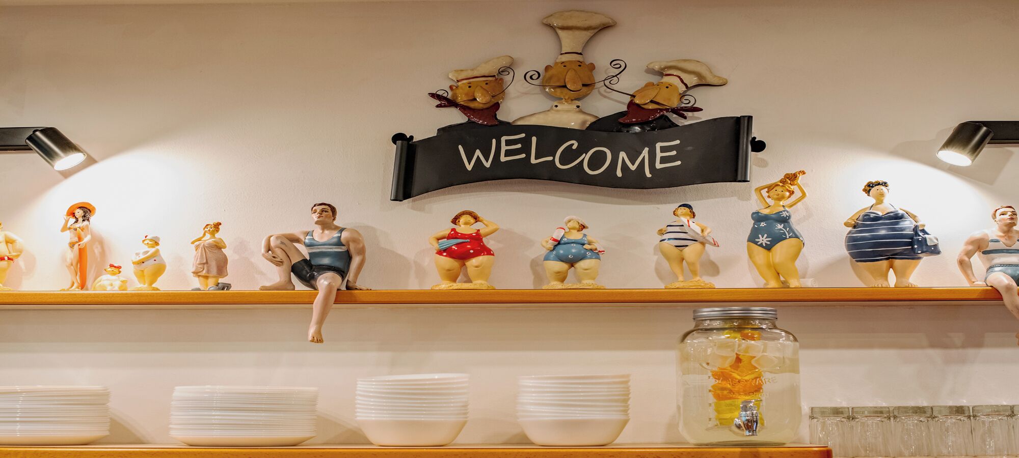 A reception area with a 'WELCOME' sign above a shelf displaying figurines and a jar of snacks.