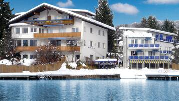 Un hotel con un cartel que dice "Barry-Memel See-Hotel" junto a un lago rodeado de paisajes nevados.