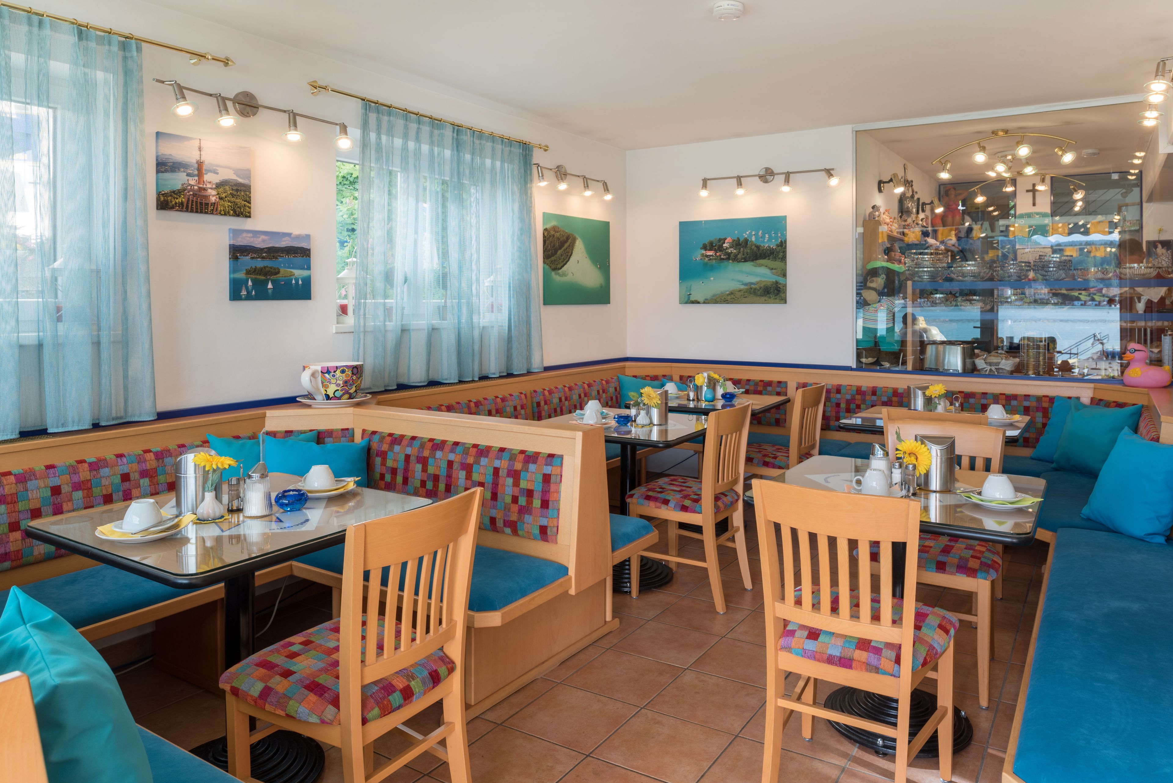 A restaurant with booths and tables, featuring artwork on the walls and a view through the window.