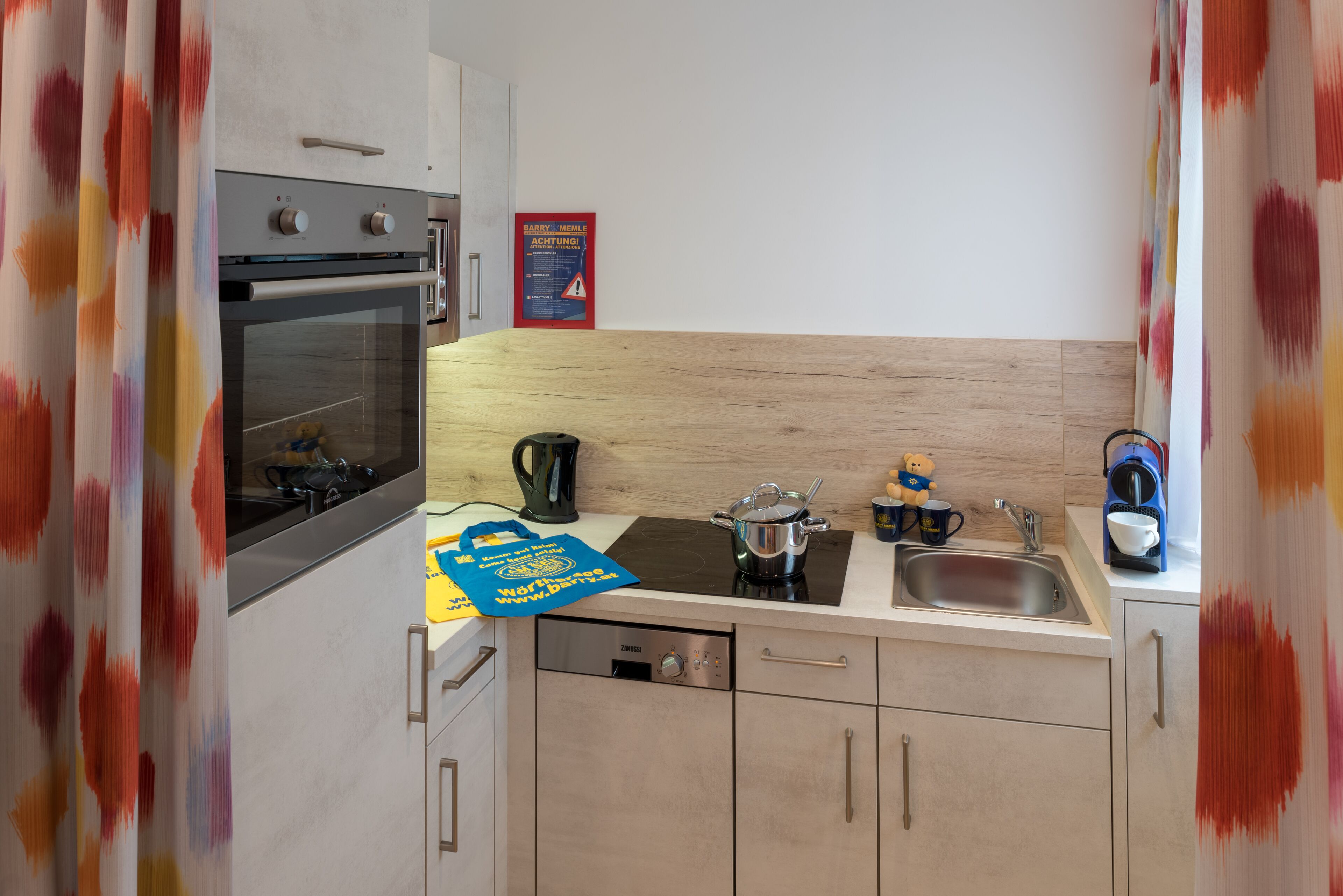 Una cocina equipada con estufa, horno, lavaplatos y una cafetera.