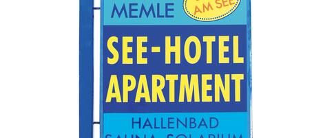 Señal para el Apartamento See-Hotel en Hallenbad, con la etiqueta 'Direkt AM SEE' y una flecha que indica 'Libre'.