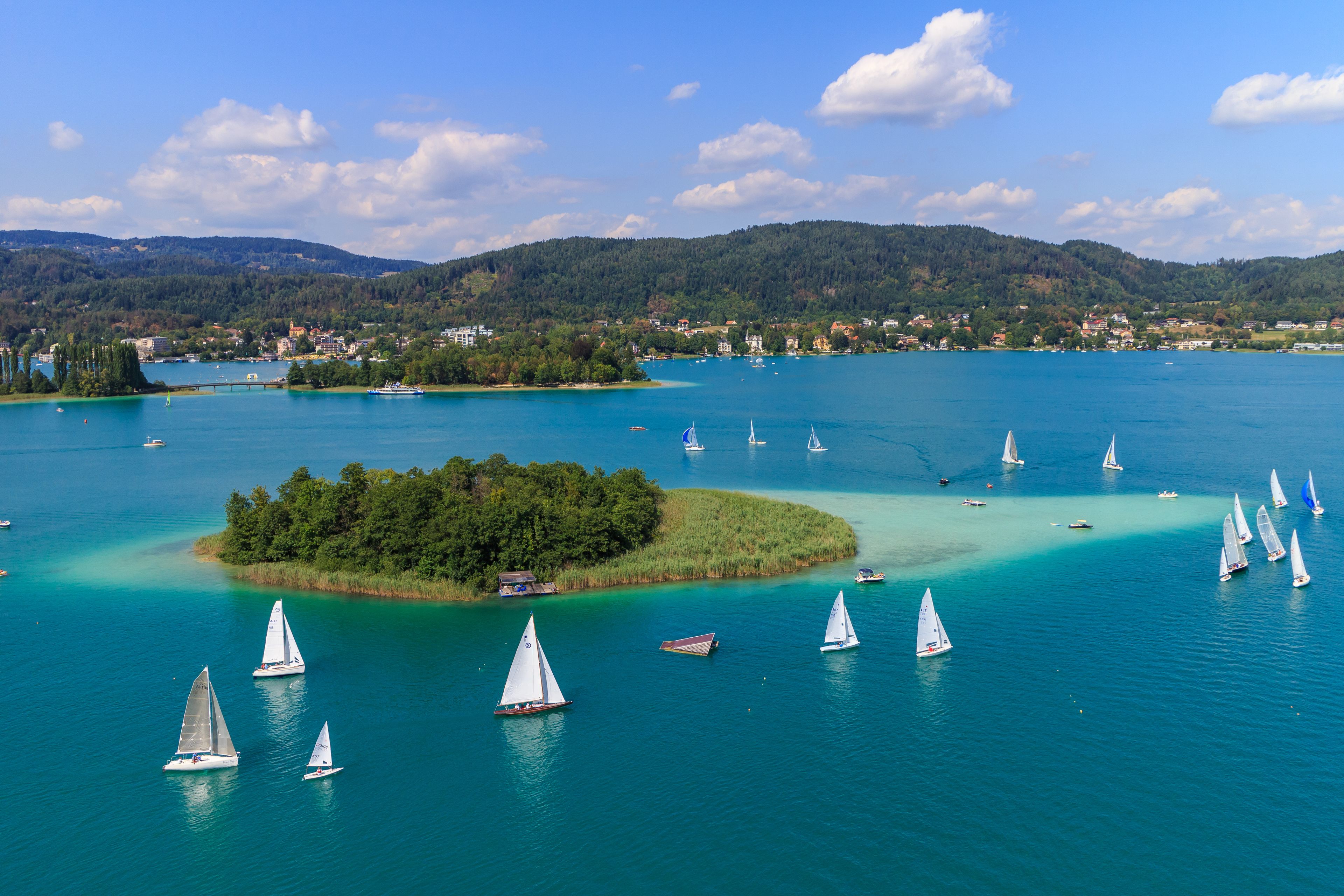 Un lago con veleros y una isla boscosa.