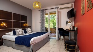 A bedroom with a bed, a desk, a chair, a television, and a window with curtains.