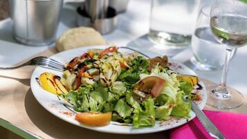 Une assiette de salade avec des légumes grillés et une fourchette posée sur une table.