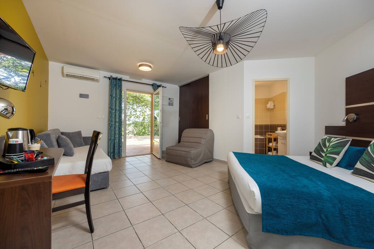 Een hotelkamer met een bed, een bureau met koffiezetapparaat, een stoel en uitzicht op het omliggende landschap.