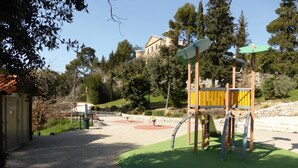 A playground with a climbing structure, a bench, and a small building.