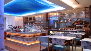 Um restaurante com área de bar, mesas e um teto decorativo.
