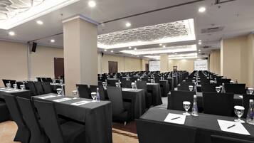 Uma sala de conferências com mesas, cadeiras e garrafas de água dispostas em fileiras.