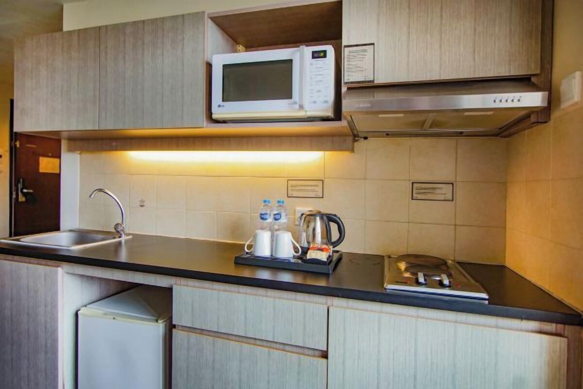 Een kleine keuken met een magnetron, waterkoker en een spoelbak.