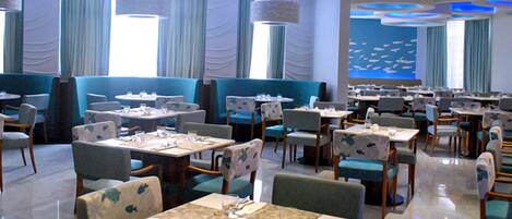 A restaurant with multiple tables and booths, blue and white decor, and a large wall mural.