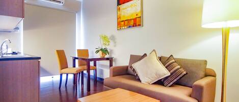 A living area with a sofa, a coffee table, a dining table with chairs, and a lamp.
