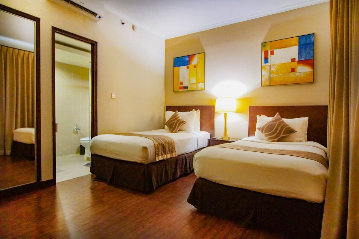 Une chambre d’hôtel avec deux lits, une salle de bain et des œuvres d’art aux murs.