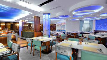 A modern restaurant with multiple dining tables and chairs, featuring a blue and white color scheme and a nautical theme.