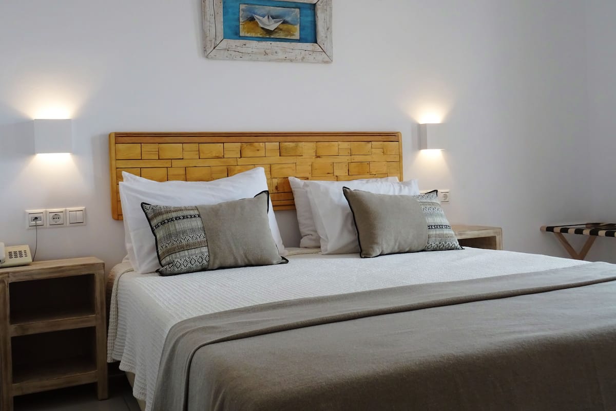 A neatly made bed with a wooden headboard, two bedside tables with lamps, and a framed painting above the bed.