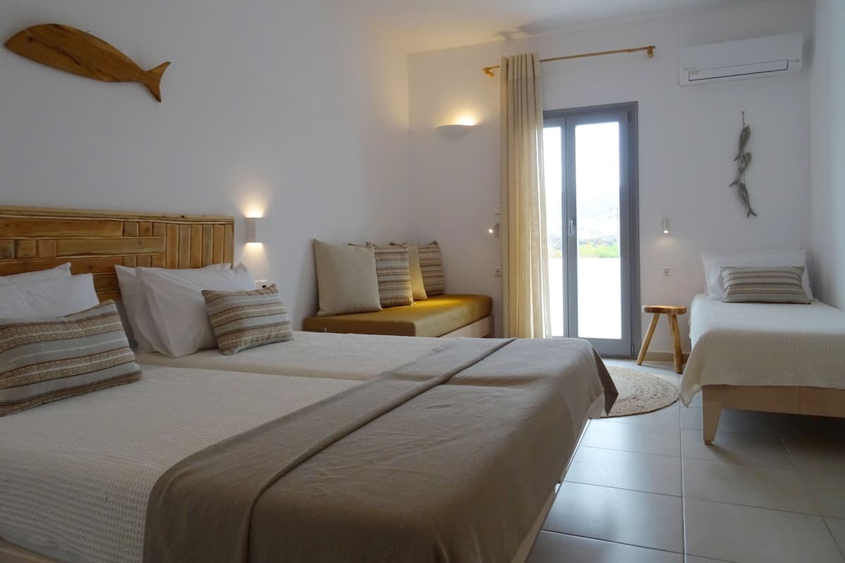 A hotel room with two beds, a wooden headboard, a fish decoration, a curtain, and a view through the window.