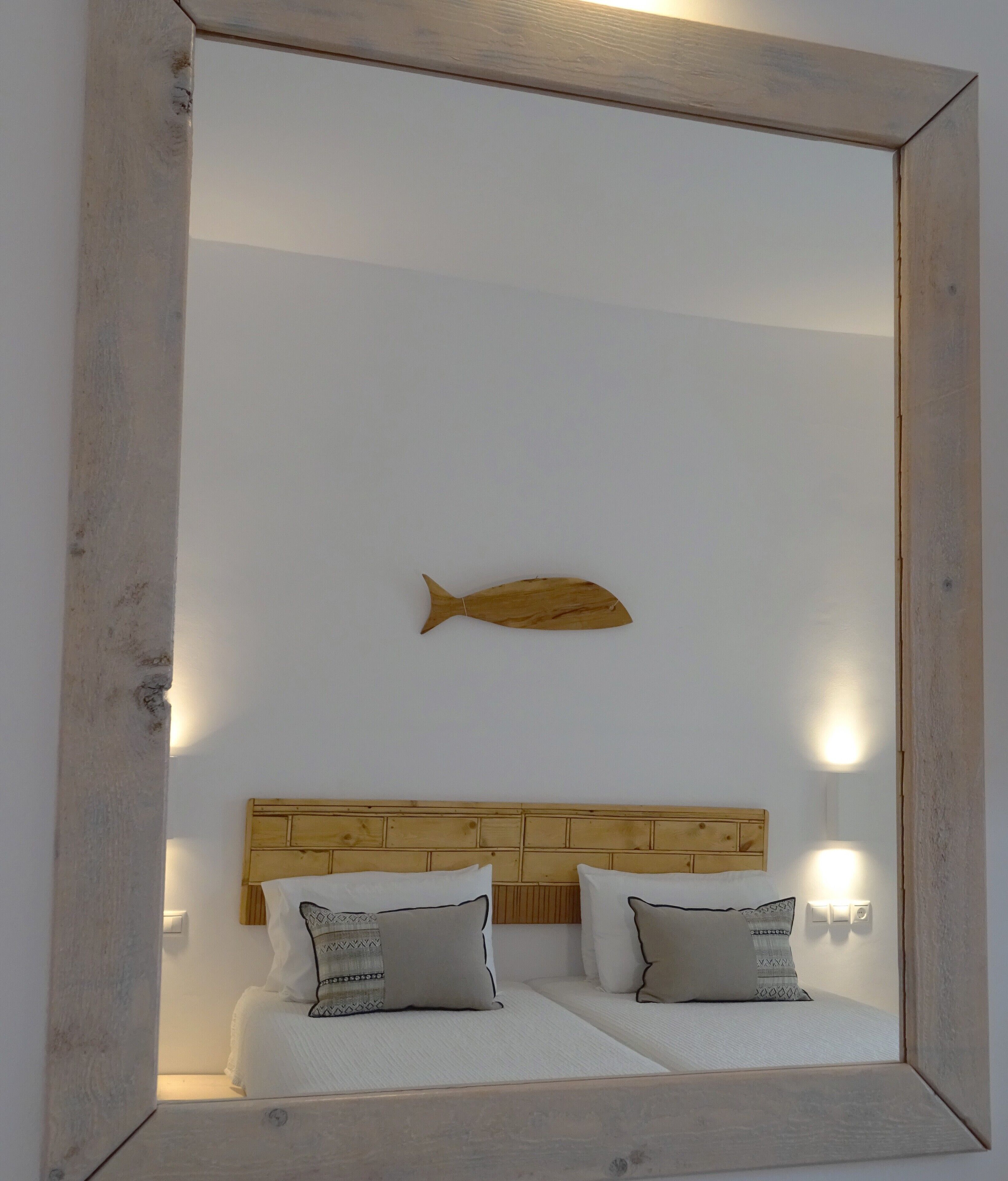 Une chambre à coucher avec une tête de lit en bois, deux lits et une décoration murale représentant des poissons.