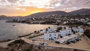A coastal town with white buildings, a marina, and a sunset over the hills. - Paros Bay Hotel (Paros)
