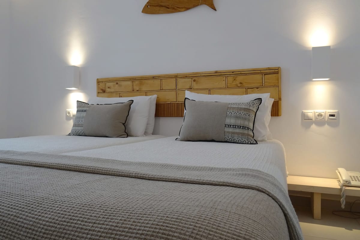 A neatly made bed with a wooden headboard, two bedside tables, and a wall-mounted telephone.