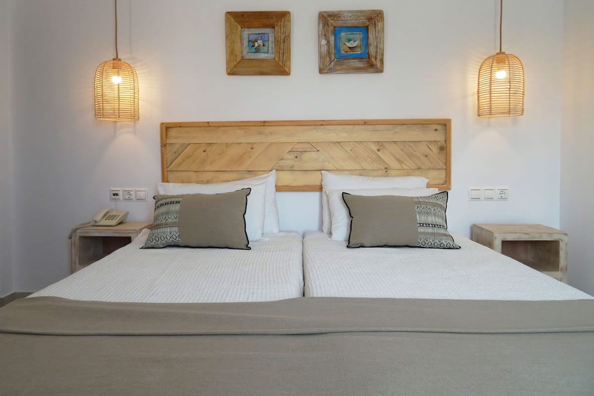A double bed with a wooden headboard, two bedside tables, and two wall-mounted lamps.