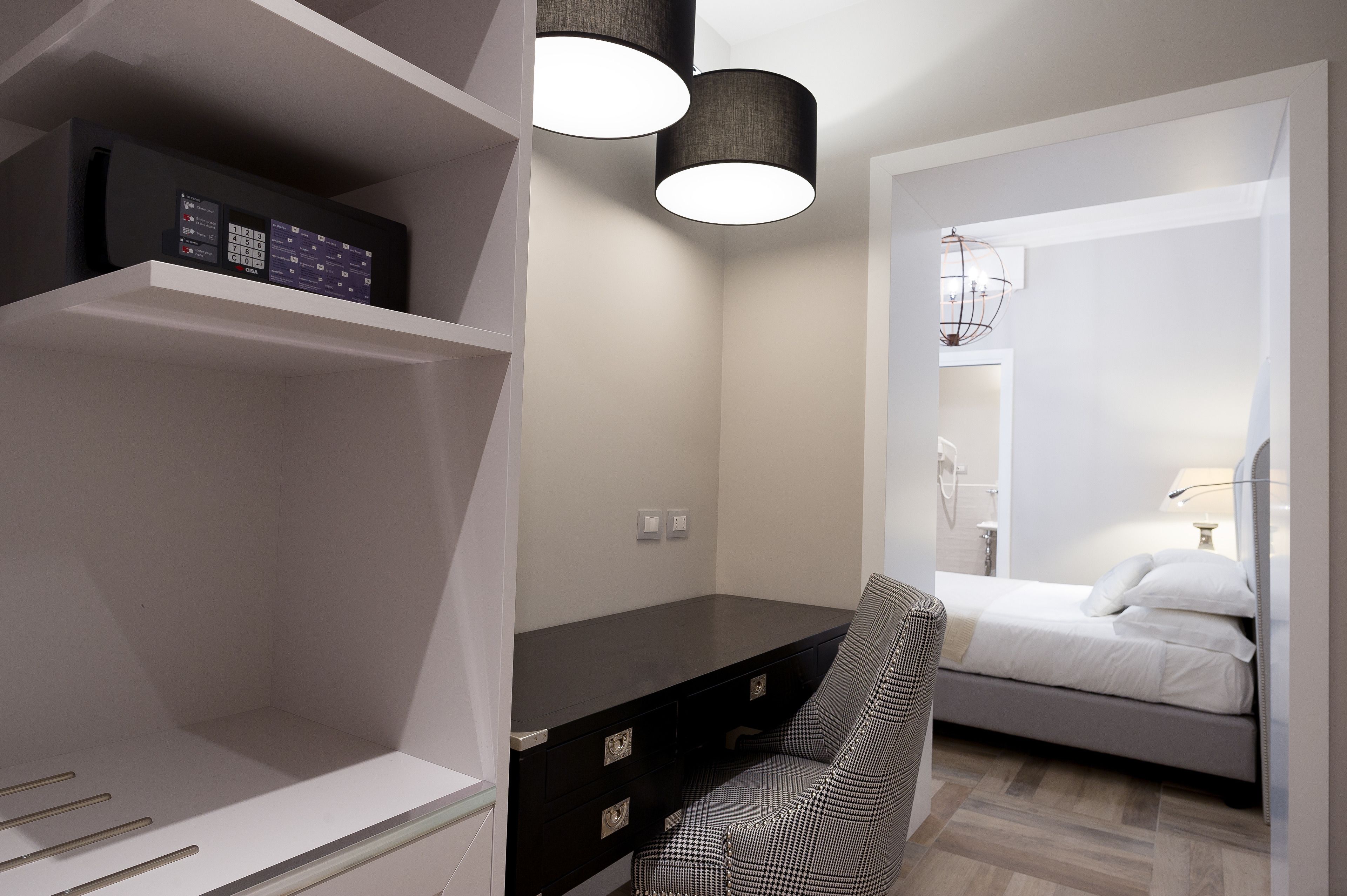 Quarto moderno com cama, escrivaninha e cadeira. Duas luminárias pendentes estão sobre a escrivaninha.