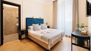 Una habitació d'hotel moderna amb un llit gran, una taula de nit, un petit escriptori i una televisió.