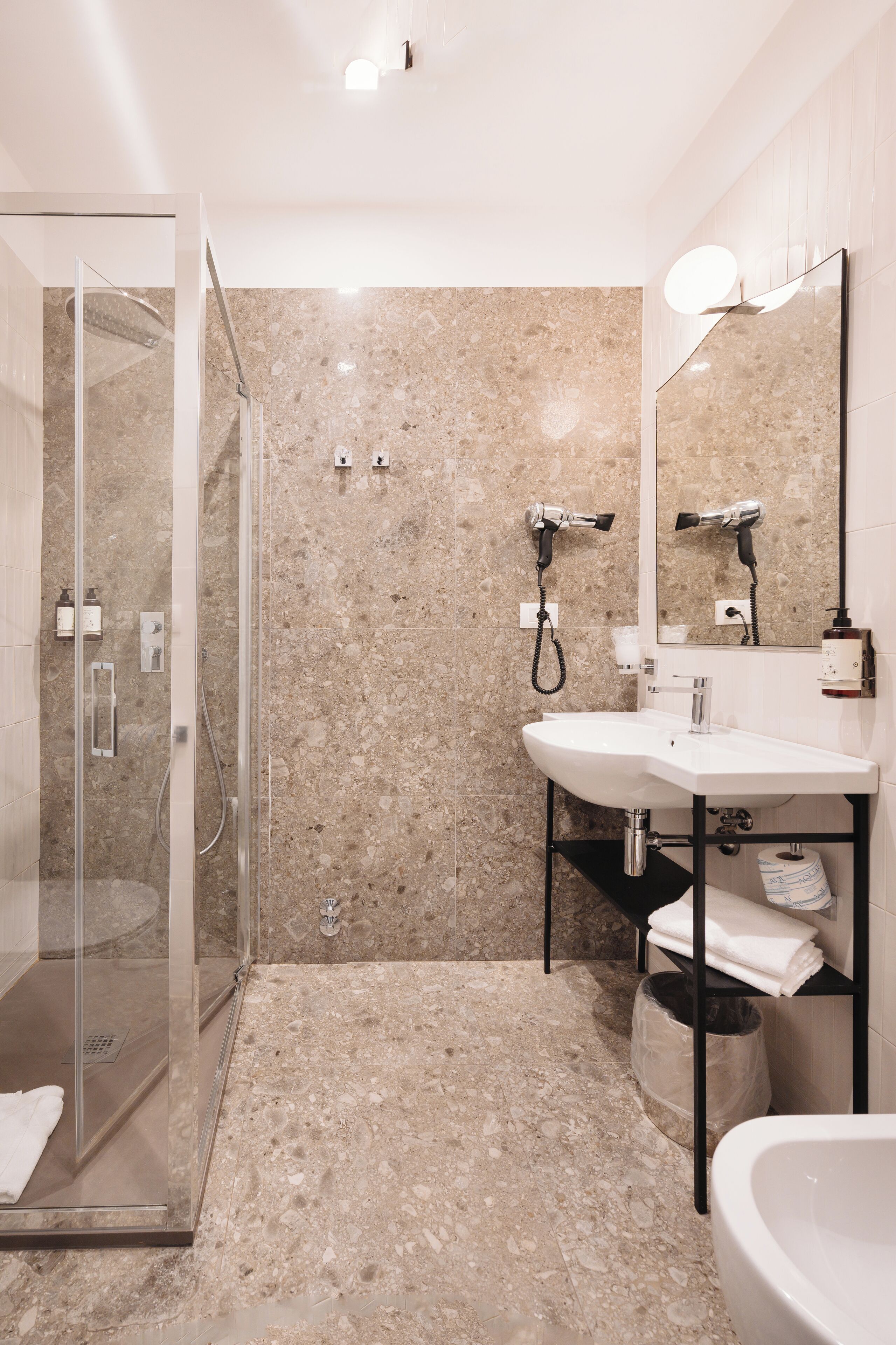 A modern bathroom with a glass-enclosed shower, a white sink, and a large mirror.