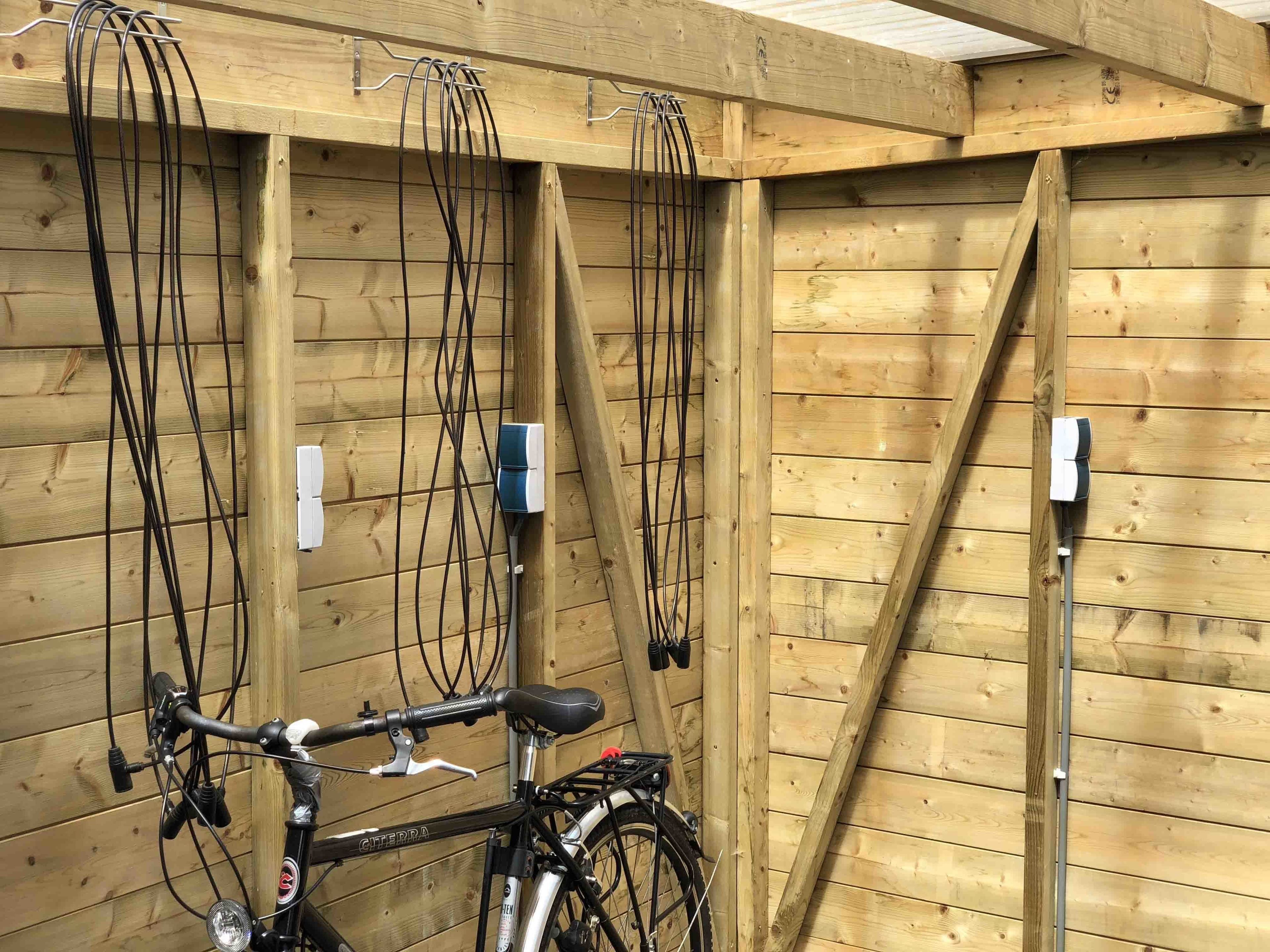A bicycle secured to a wooden wall with multiple electrical outlets.