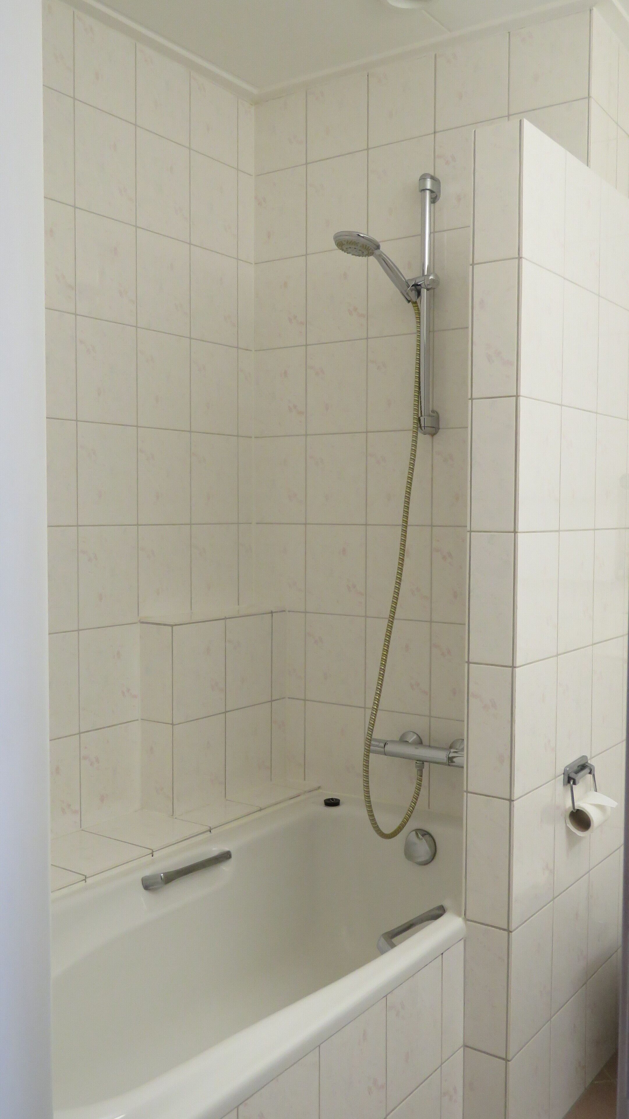 A bathroom with a bathtub, a showerhead, and a toilet.