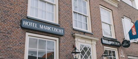 A hotel named 'Hotel Marktzicht' with a brick facade, large windows, and outdoor seating area.